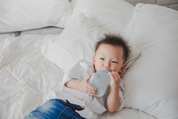 Asian Japanese Family Brother drinking breast brother wearing white shirt carrying child posing for photo on bedroom in white room.To keep memories moment cuteness of son in childhood lifestyle happy