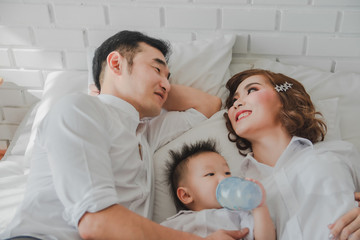 Obraz premium Asian Japanese Family father mother son wearing white shirt posing for photo on white bedroom in white room.To keep memories moment cuteness of son in childhood lifestyle happy
