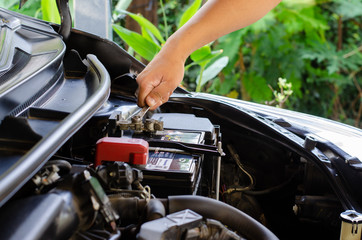 A man used a wrench to change the car battery.