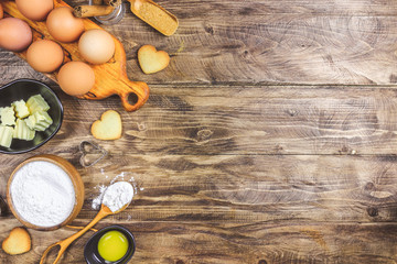 Valentine's Day baking culinary background. Ingredients for cooking on wooden kitchen table, baking recipe for pastry. Heart shape cookies. Top view. Flat lay.