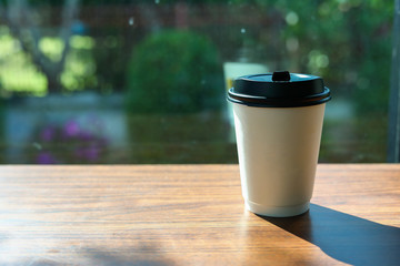 take away cup for hot coffee drink put on wooden table in cafe