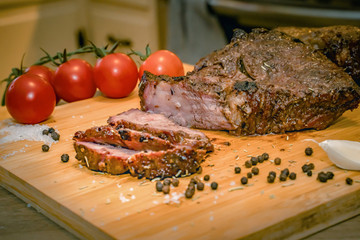 Baked meat, garlic and papper on a wooden background. Roast beef.Roast beef on cutting board with salt and pepper.