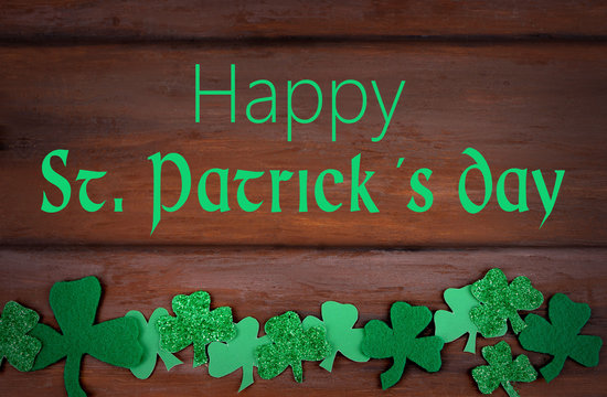 Saint Patrick's Day image of glittered and felt green sharmocks on a rustic wooden background. Happy St. Patrick's Day message