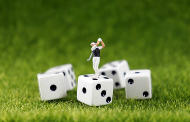 A miniature golfer on a dice with a lawn background.