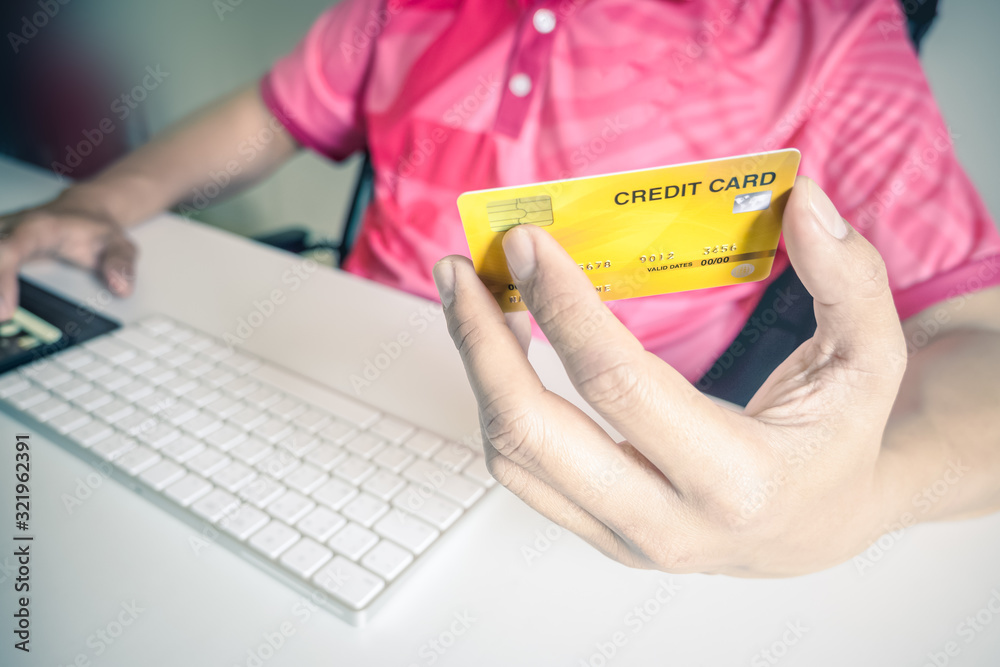 Poster man paying with credit cards on computer at home.