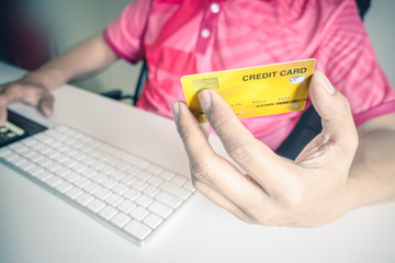 Fototapeta premium Man paying with credit cards on computer at home.