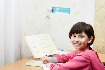 Smiling asian schoolgirl doing homework.
