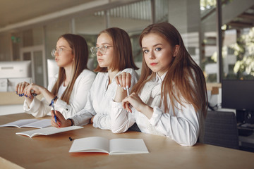 Students in a park. Girls lying on a grass. Friends with a notebooks.
