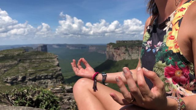 A girl meditating in a paradisic mountain with the view of the beautiful geological formation of chapada diamantina national park.