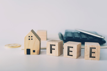 Tax word on wooden cube with objects as gold coin, calculator and mini home model behide white clean background. Business financial loan property.