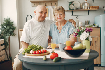 Coyple in a kitchen. Grandparents sitting at home. Woman with vegetables