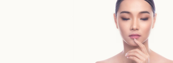 Fototapeta premium Beautiful Young Asian Woman with Clean Fresh Skin isolate on white background. Spa, Face care, Facial treatment, Beauty and Cosmetics concept. Finger on lips, eye close. Banner frame.