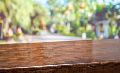 Tropical spring background.Empty diagonal brown wooden table with blur tree in park boekh...