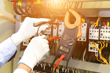 electrician measurements with multimeter tester in control panel.