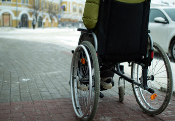 Obraz premium A disabled person in a wheelchair moves around the city in winter.
