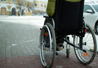 A disabled person in a wheelchair moves around the city in winter.