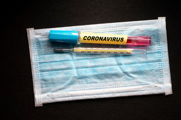 Coronavirus Blood Test with thermometer and mask on black background.