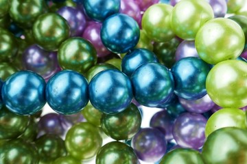 colored pearls close-up. pearl beads round background.blue, purple, green  beads texture.Beautiful decoration background in cold colors.