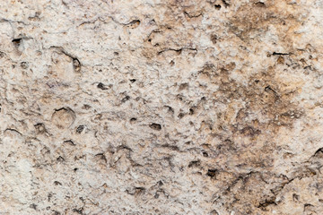 A grunge texture background of an old  stone relief wall with holes