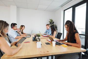 Creative young multi-ethnic team sitting at big office table and working on project