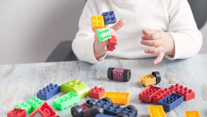 Little girl playing with colorful construction plastic blocks.