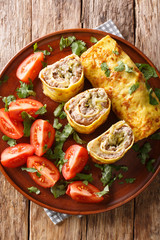 omelet roll stuffed with meat, cheese and pickles close-up in a plate. Vertical top view