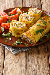 Brizol omelet stuffed with minced meat, cheese and pickles close-up in a plate. vertical