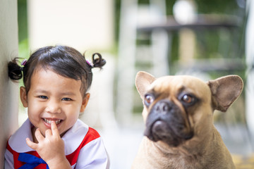 Cute school girl sitting with her french bulldog outdoor.