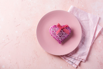 Valentines day table setting with pink plate and gift heart on pink light background.