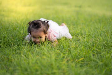 cute little girl lying on grass at park.