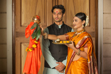 Maharashtrian couple in traditional dress celebrating gudi padwa festival holding a pooja plate.