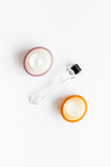Dermaroller for mesotherapy near creams on white background top-down flat lay