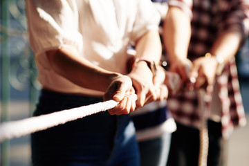 Cropped image of coworkers playing tug of war for developing cooperation and support in business team