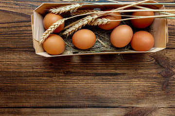 farm brown eggs with straw in birch box wooden background close-up with copy space