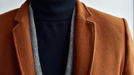 Close up of mens fashionable brown woolen coat combined with grey sweater.  Selective focus.