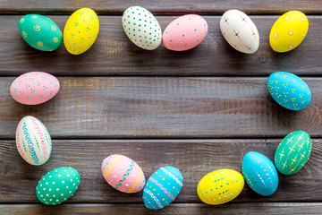 Colorful Easter eggs frame on dark wooden background top-down copy space