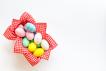 Easter eggs painted in basket on white desk top-down copy space
