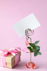Gift box with a pink bow. Gift for Valentine's Day or March 8th. Business card, holiday card on a pink background. Postcard February 14, Valentine's Day. Vertical photo. Copy space.