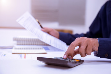businessman working on a desk with a calculator to calculate the numbers finance accounting year 2018 concept.