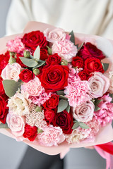 European floral shop. Red and pink Beautiful bouquet of mixed flowers in womans hands. the work of the florist at a flower shop. Delivery fresh cut flower.