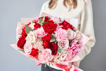 European floral shop. Red and pink Beautiful bouquet of mixed flowers in womans hands. the work of the florist at a flower shop. Delivery fresh cut flower.