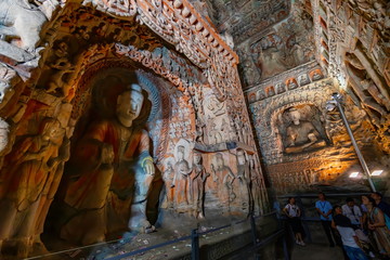 Painted caves with buddha and monk statues in niches. World cultural heritage site and Buddhist Caves Art Treasure Houses in Yungang Grottoes near Datong, Shanxi Province, China 