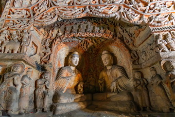 Fototapeta na wymiar Buddhist Caves Art Treasure Houses. Painted caves with hundred of ancient colored buddha and monk statues in niches. Yungang Grottoes,Datong, Shanxi Province, China 
