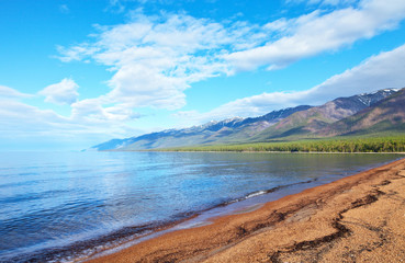 Baikal Lake on a sunny June day. The long sandy beach of Barguzin Bay is famous for tourists with calm warm water and beautiful mountain landscapes. Natural summer background