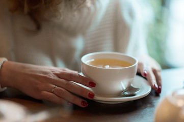 Woman holds white cup with tea