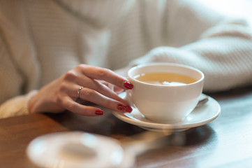 Woman holds white cup with tea
