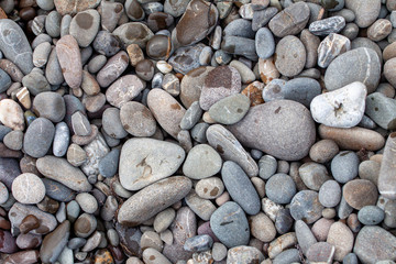 sea pebbles colored granite on the beach background stones. The shore of the beach with sand and pebbles washed by the waves of the sea.