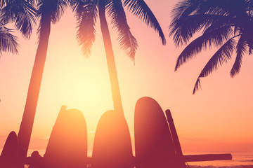 Surfboard and palm tree on beach background.