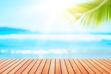 Blur tropical beach with bokeh sun light wave and palm tree on empty old wood table abstract background.