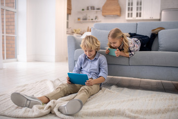 Boy sitting on the floor, girl lying on sofa